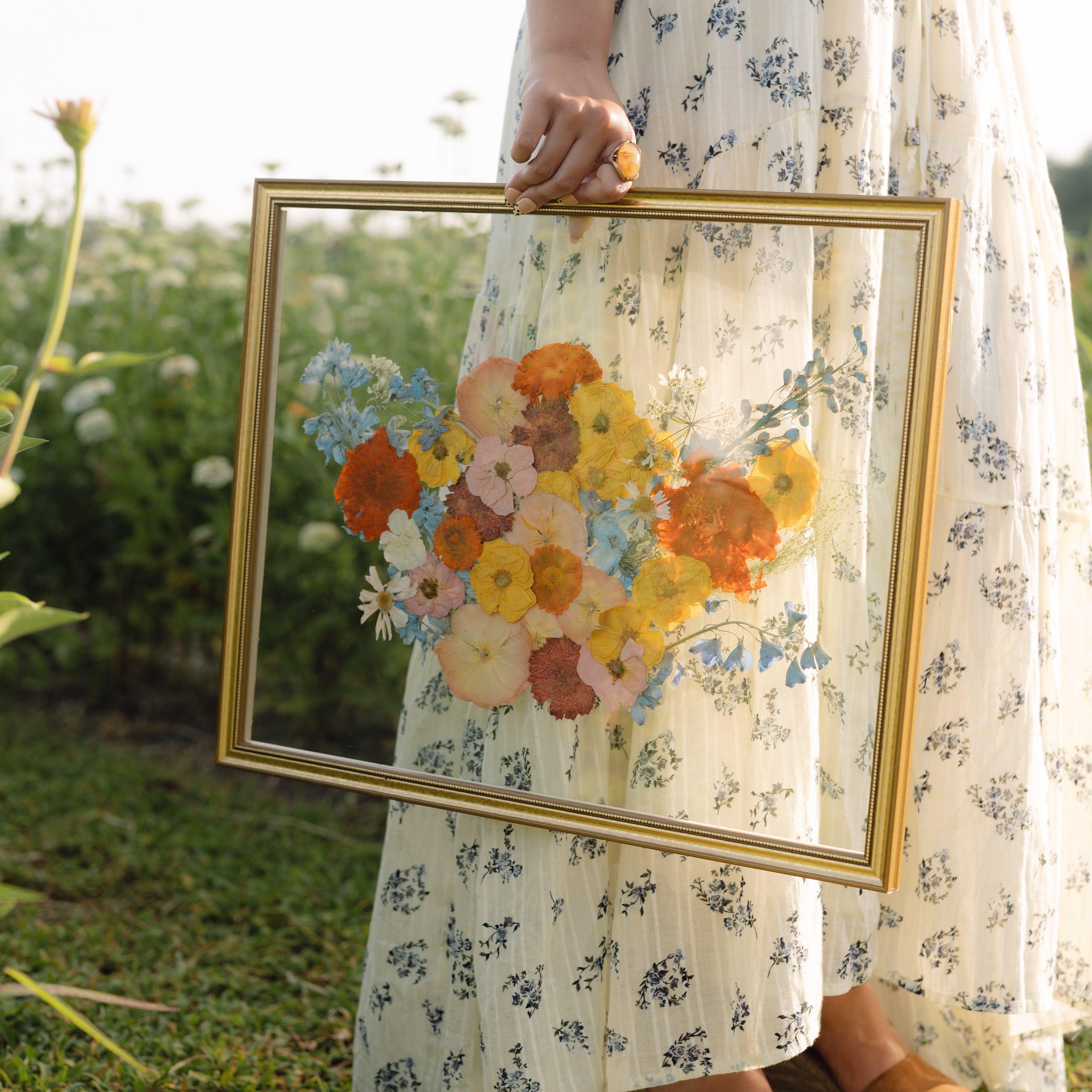 Person holding a framed floral painting outdoors