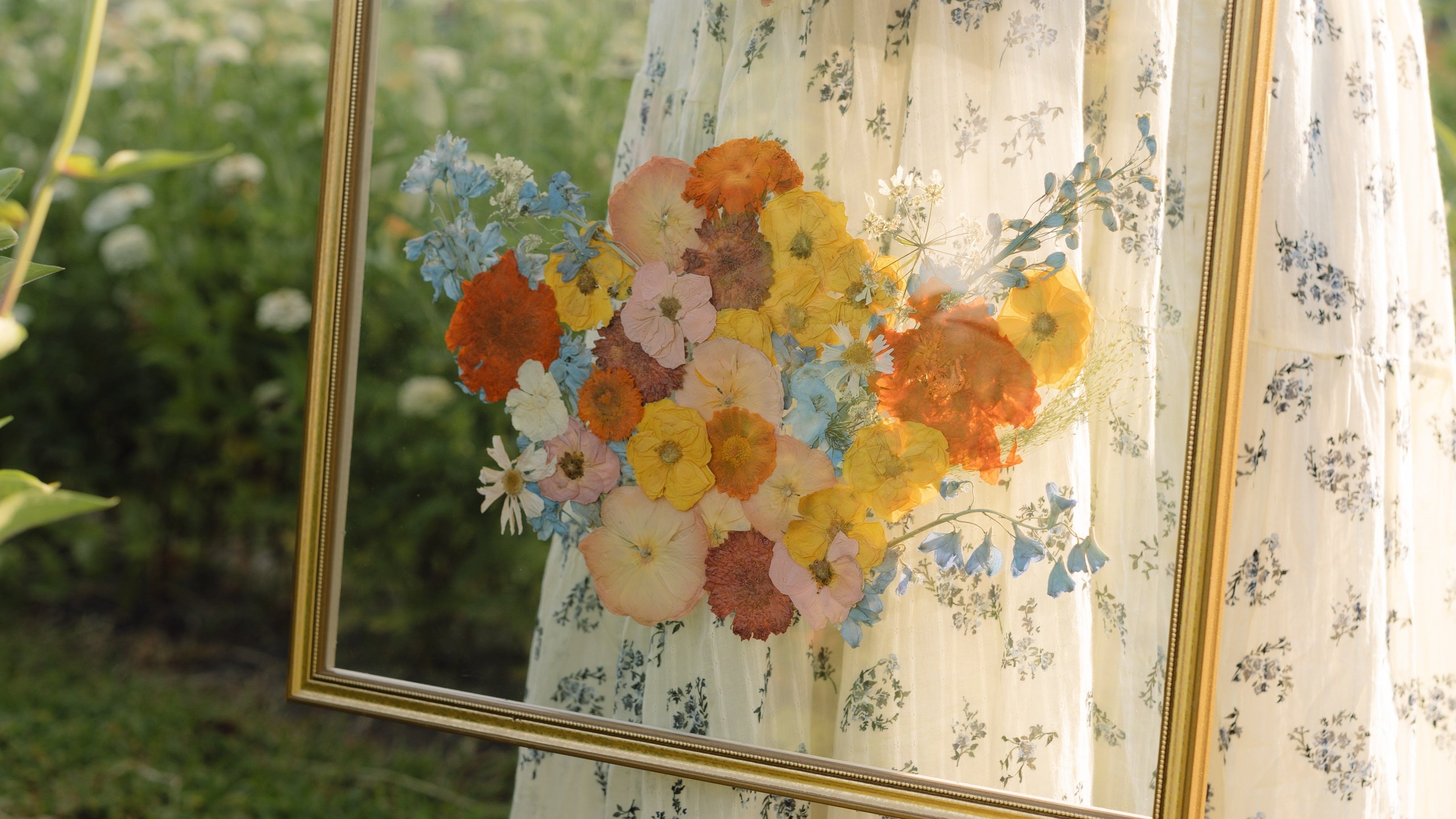 Person holding a framed floral painting outdoors