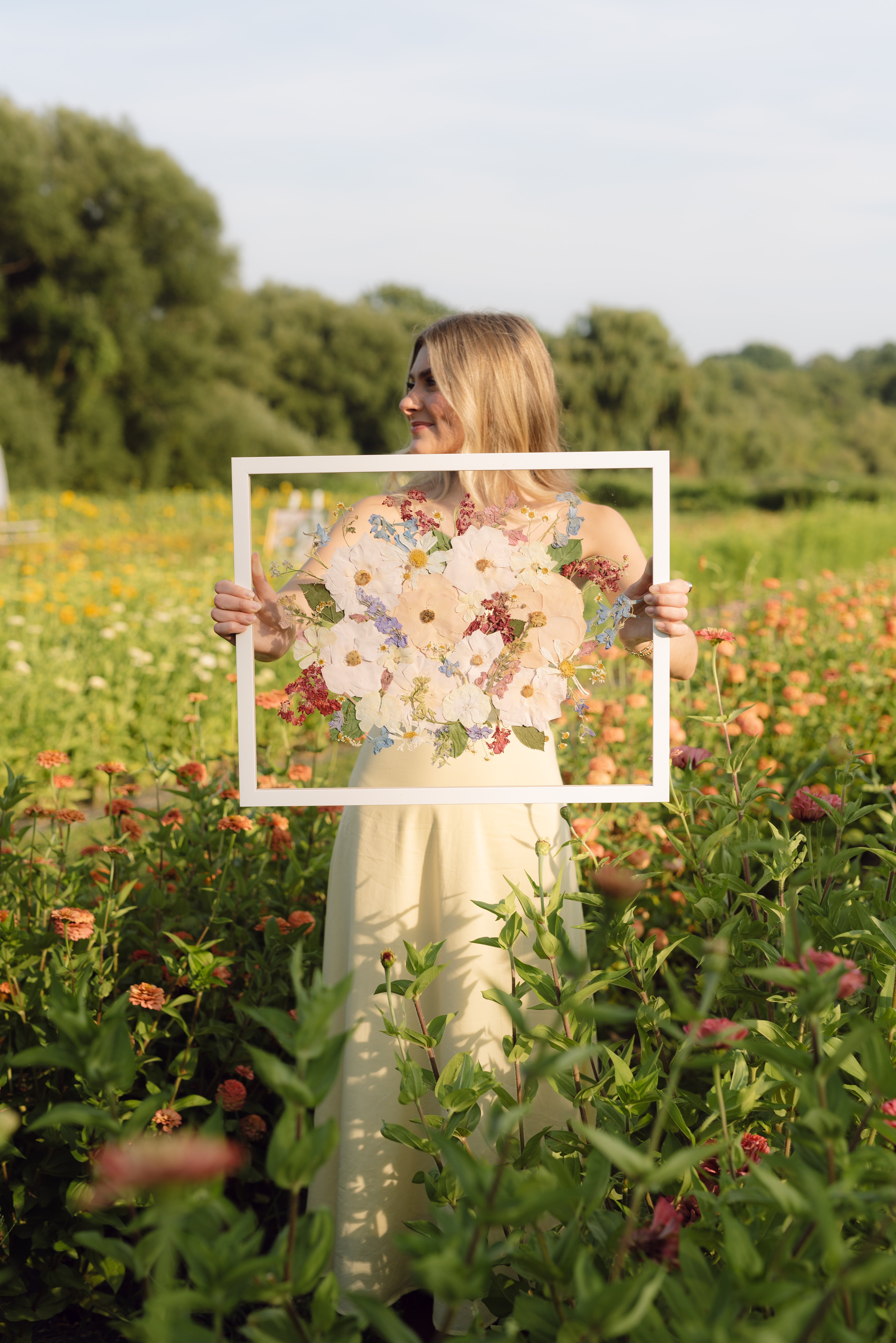 Woman holding a bouquet of pressed flowers in a field with a frame overlay