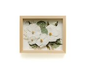 Framed artwork with white flowers and green leaves on a white background
